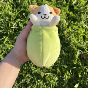 Peluche de Benjamín el gato aceituno. También es llavero y se puede sacar de la aceituna. Fondo de césped verde.