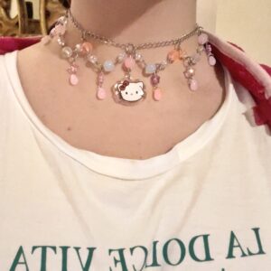 Collar sanrio artesanal con abalorios rosas y blancos que cuelgan de una cadena plateada. En el centro tiene una hello kitty