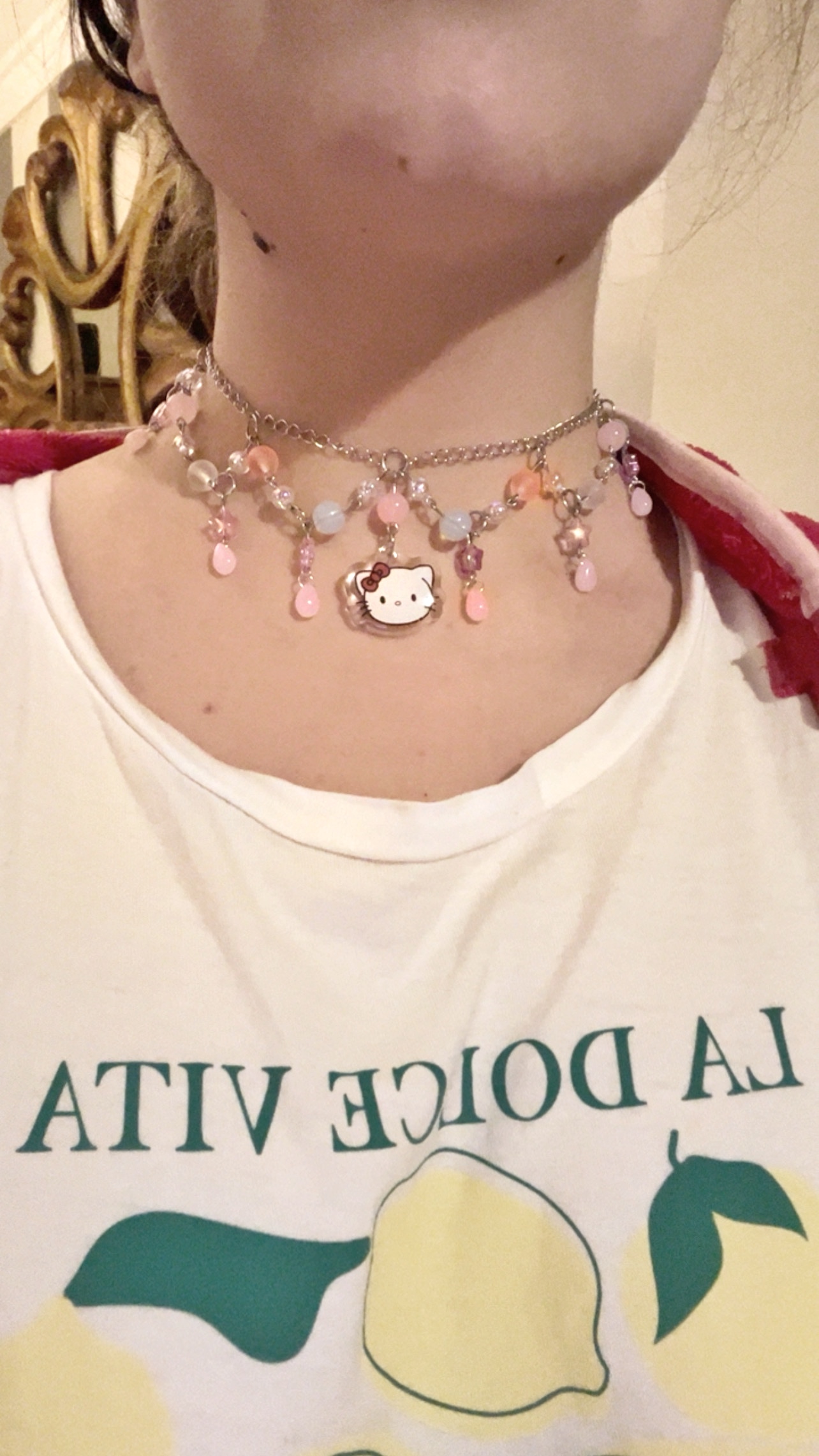 Collar sanrio artesanal con abalorios rosas y blancos que cuelgan de una cadena plateada. En el centro tiene una hello kitty