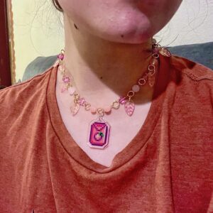 Collar stardew valley. Collar dorado con cuentas rosas y con una semilla de melón del videojuego stardew valley en el centro