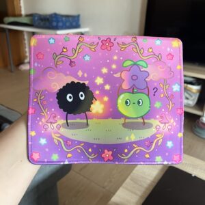Alfombrilla de ratón con fondo morado que presenta a un susuwatari de Studio Ghibli entregándole una estrella a un junimo verde de Stardew Valley