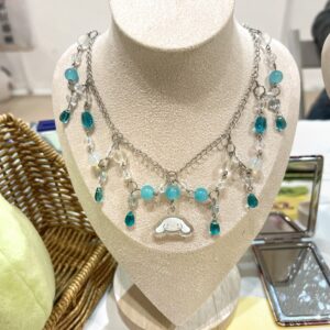 Collar sanrio con un Cinnamoroll en el centro con cuentas de vidrio azules que cuelgan de una cadena plateada