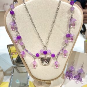 Collar sanrio con una kuromi en el centro y cuentas moradas que cuelgan de una cadena plateada