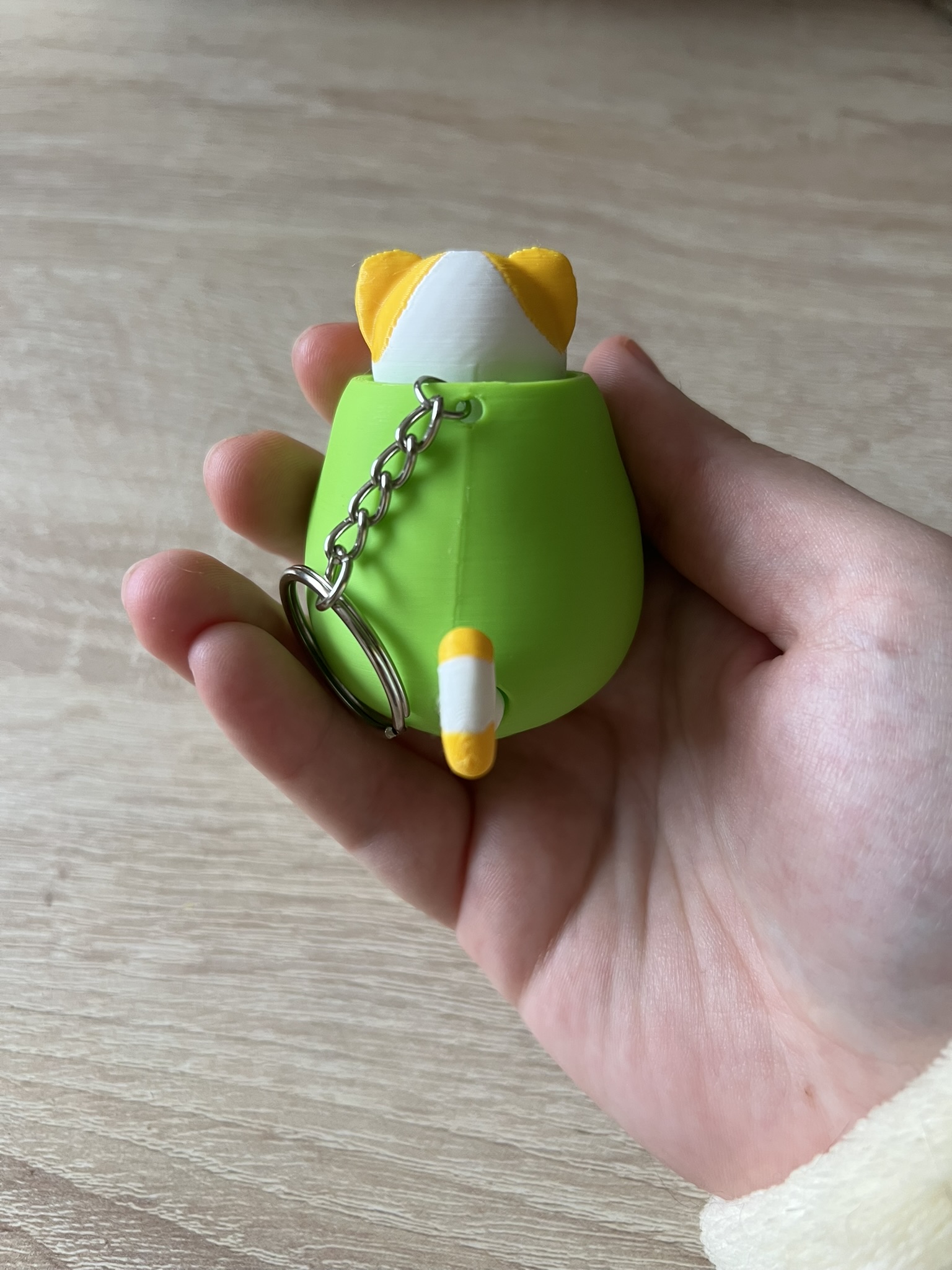 Llavero tipo clicker con impresión 3D del gato aceituno (Benjamín) que es un gato naranja y blanco metido en una aceituna verde