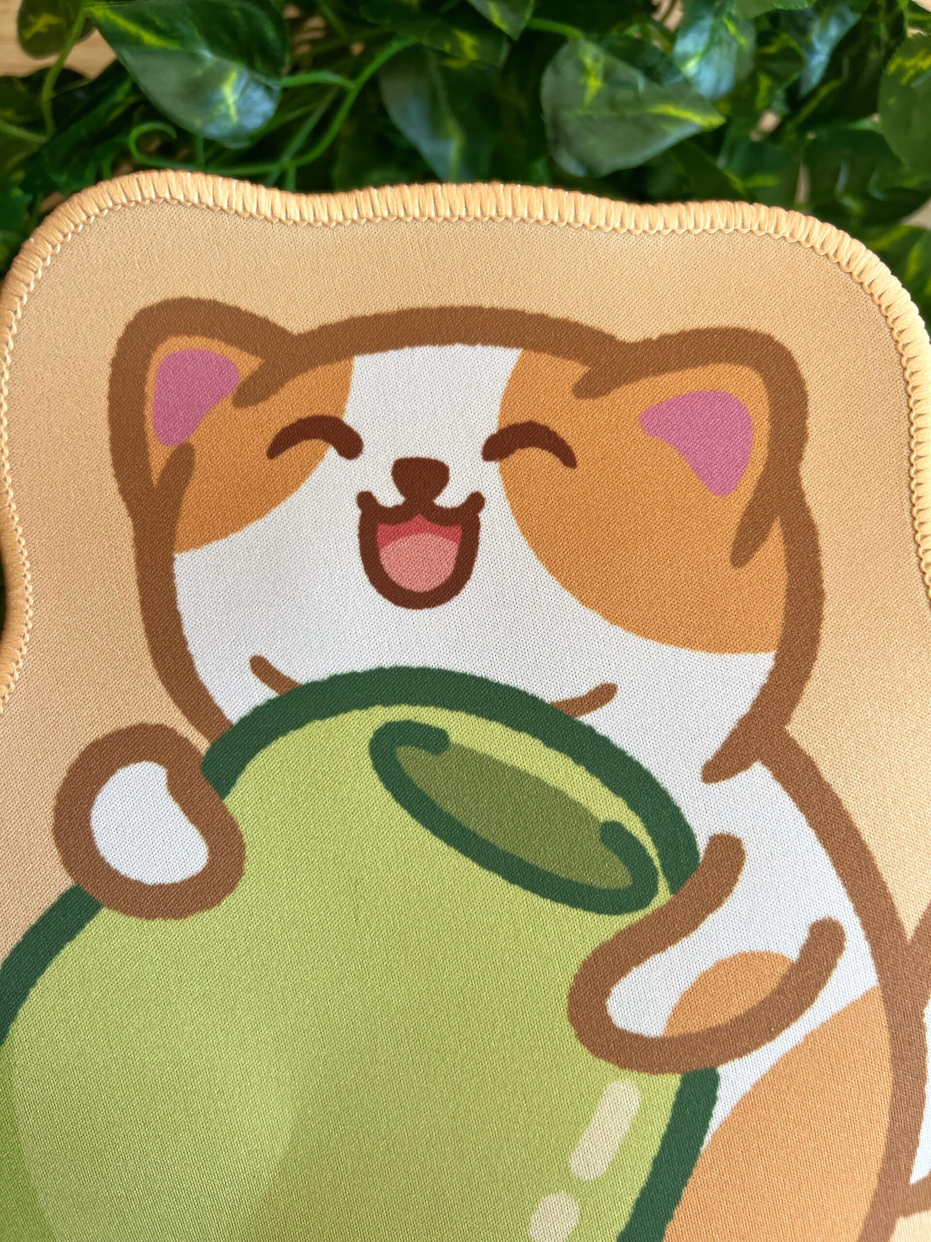 Mouse pad del gato aceituno (Benjamín) abrazando una aceituna verde. El gato está contento y es blanco y naranja